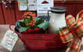 Brush Creek Bloom Bundle featuring a blooming orange kalanchoe, decorative holiday tin, greenery, ribbon, and fragrance gift items ready for gifting