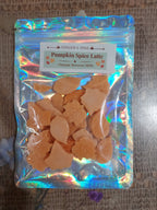 A clear holographic resealable pouch containing pumpkin spice latte organic beeswax melts, with a white label reading 'Pumpkin Spice Lattc' and 'Ginger & Pine'.