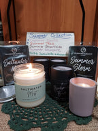 A collection of Melrosehouse Candle Co. summer-themed scented candles displayed on a green crocheted doily over burlap.