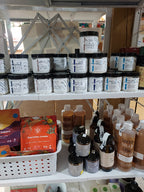 A retail display shelf filled with various skincare and cosmetic products, including white jars with blue and black lids, brown bottles, and an orange box of Salviace hand cream.