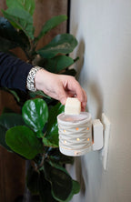 Person using a wall-mounted wax warmer with a plant in the background