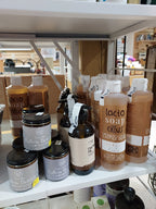 A retail display shelf stocked with various soap and lotion products, including Lacto Soap 'clim' in amber bottles and Hallowen Butter jars, photographed from an angled overhead perspective.