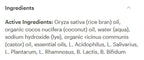 A close-up of an ingredients list on a white background, showing text that reads 'Ingredients' and 'Active Ingredients: Oryza sativa (rice bran) oil, organic cocos nucifera (coconut) oil, water (aqua), sodium hydroxide (lye), organic ricinus communis (castor) oil, essential oils, L. Acidophilus, L.