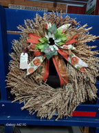 Decorative corn plume wreath with a bow on a blue surface