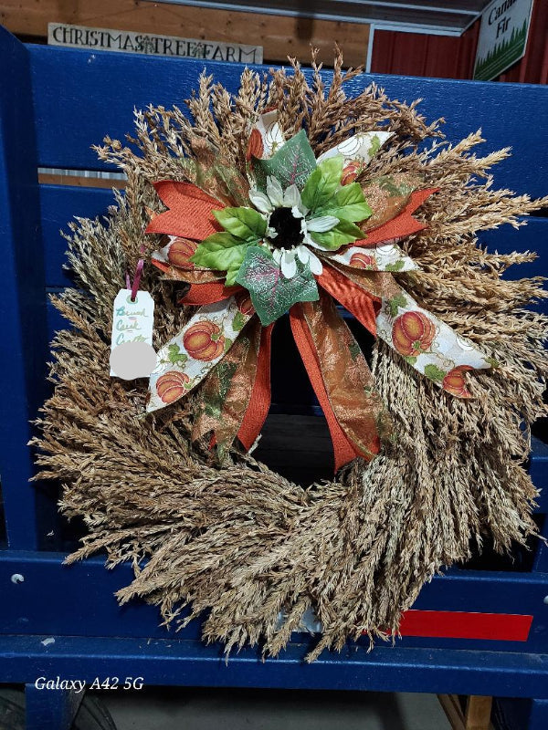 Decorative corn plume wreath with a bow on a blue surface