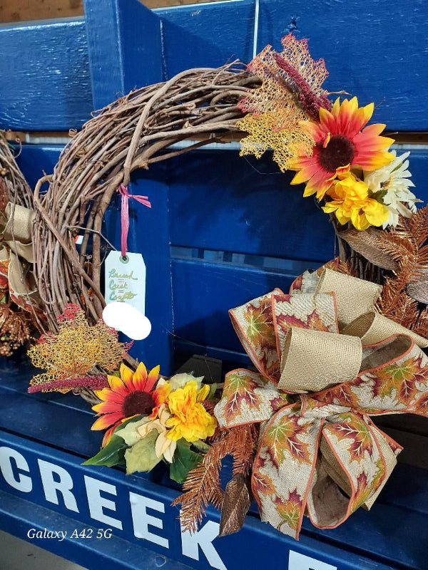 Decorative wreath with sunflowers and a bow on a blue surface